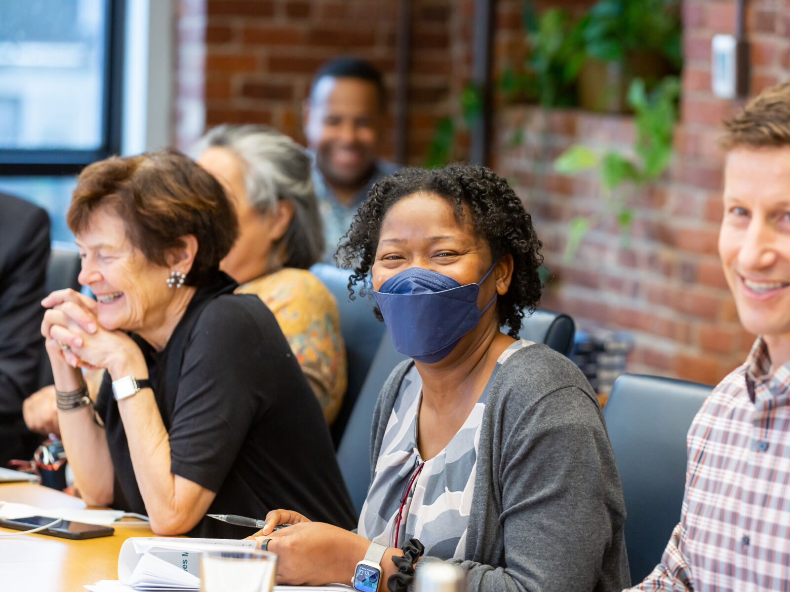 Candid photo of several Barr staff members sitting in a conference room and talking.
