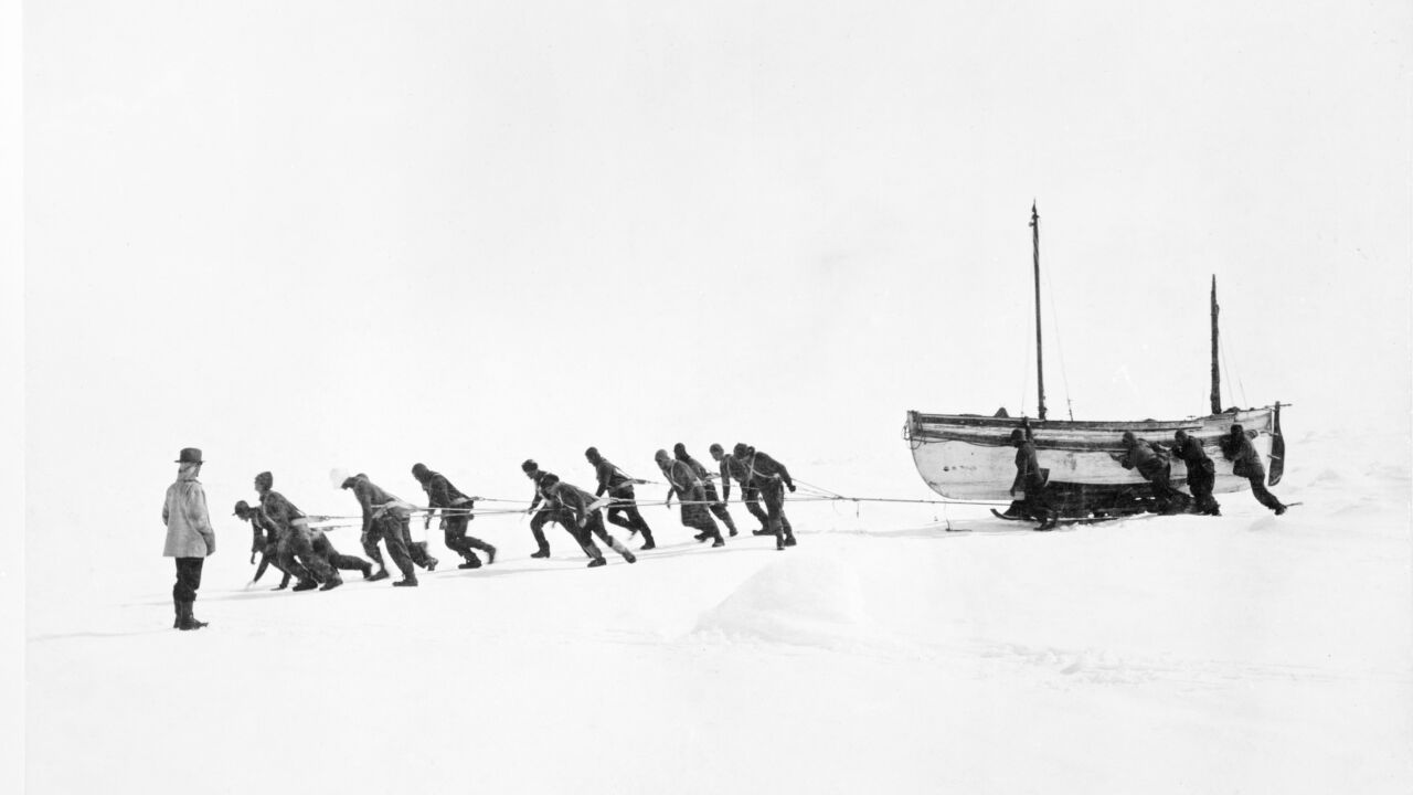 Men work together to haul a boat ashore.