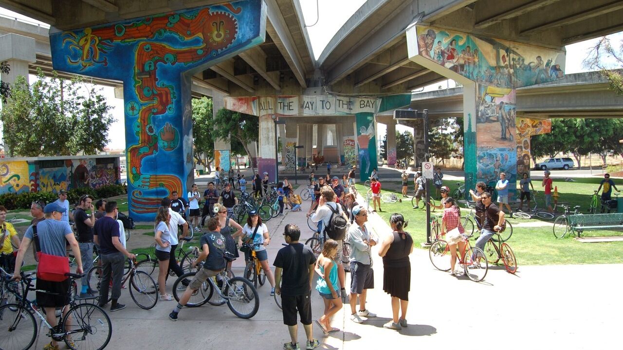 Bikers and pedestrians hang out under a street mural.