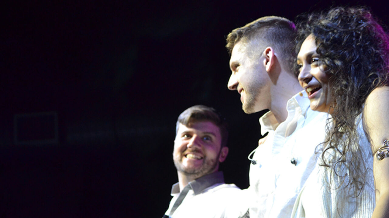 Performers smile and laugh on stage.