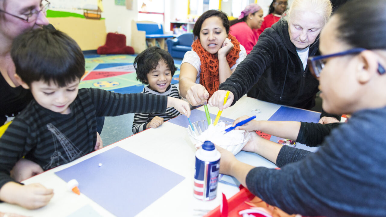 Kids and their parents paint a snowman.
