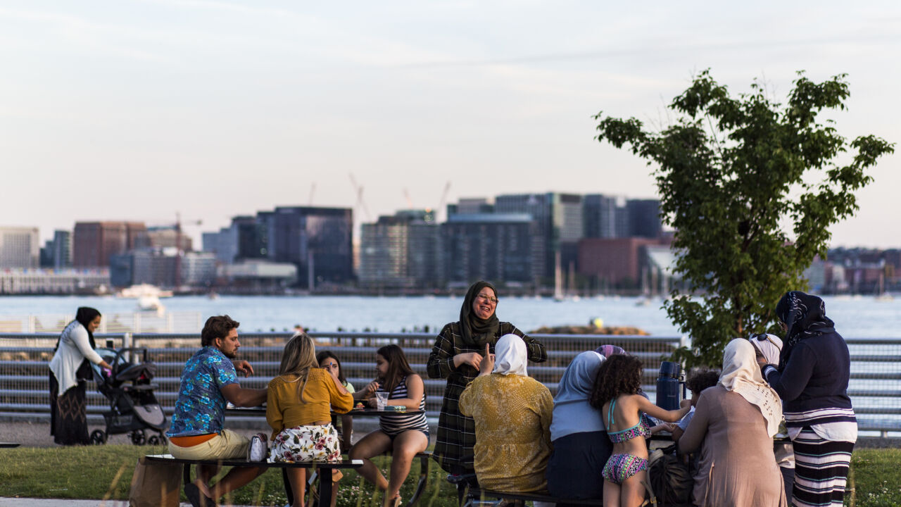 People laugh at picnic tables on Boston's waterfront.