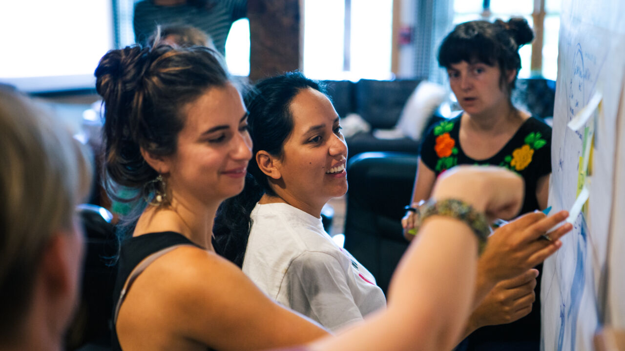Adults stick post its to a wall.