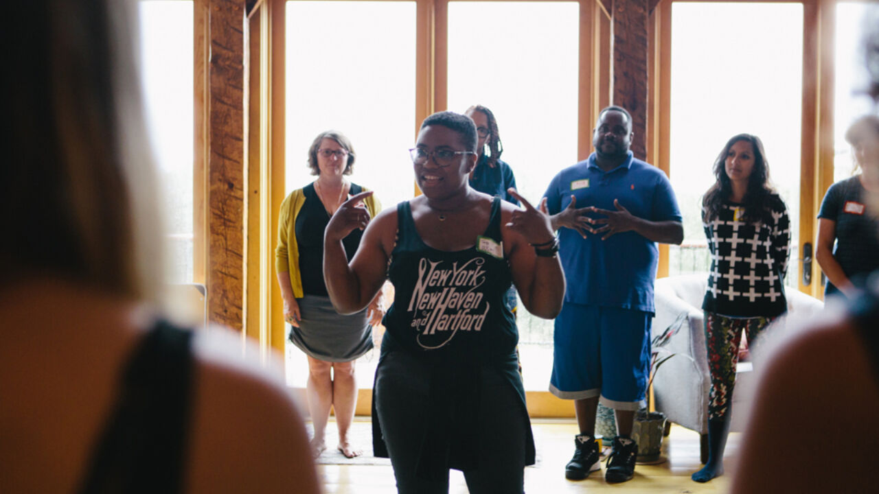 Woman talking in the middle of a circle of people.