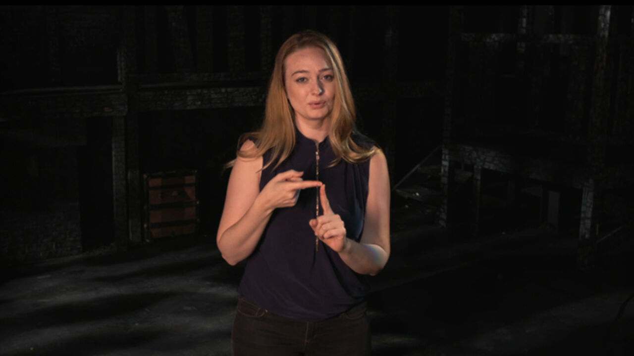 A woman signs on a stage.