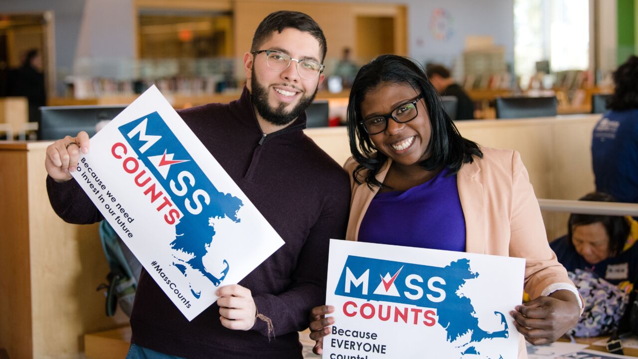 Two people hold up signs in support of the Census.