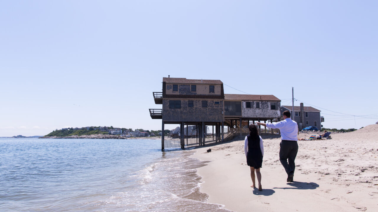 Two people walk along the beach.