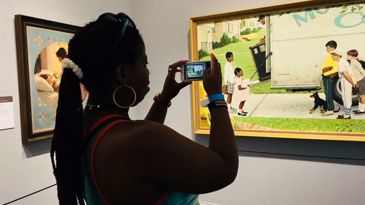 A woman tacking a picture of a normal rockwell painting of