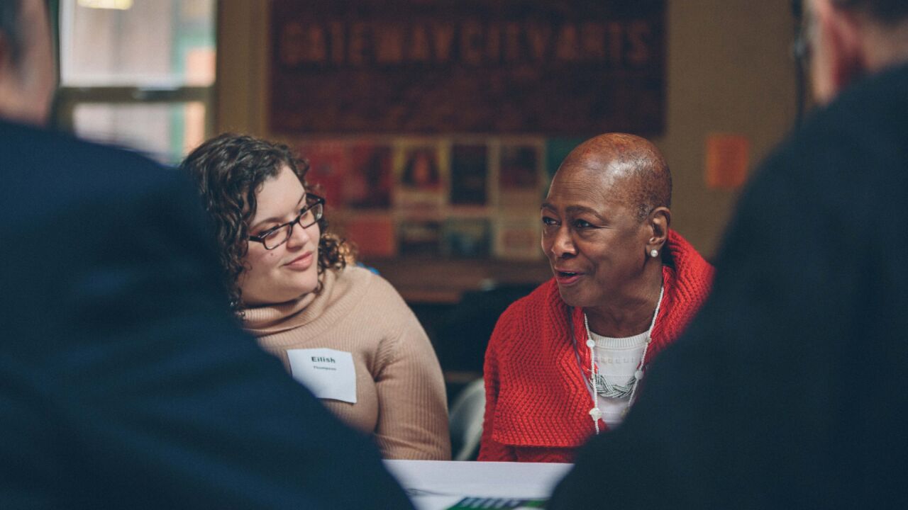 Two women talk at a round table.