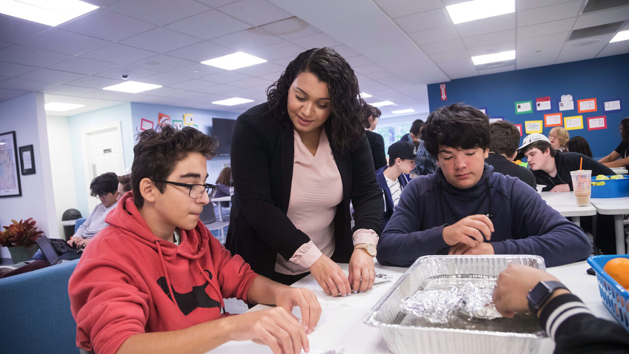 A teacher works with students on an experiment.