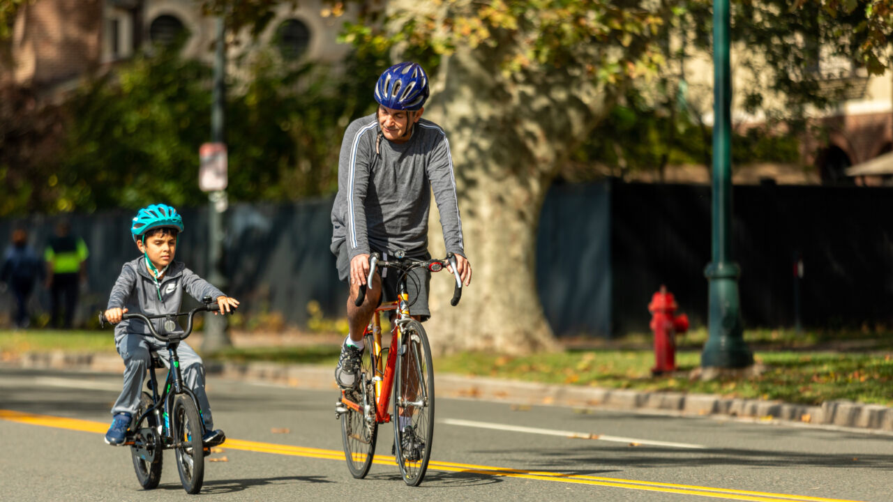 A grandfather and grandson bike outside.