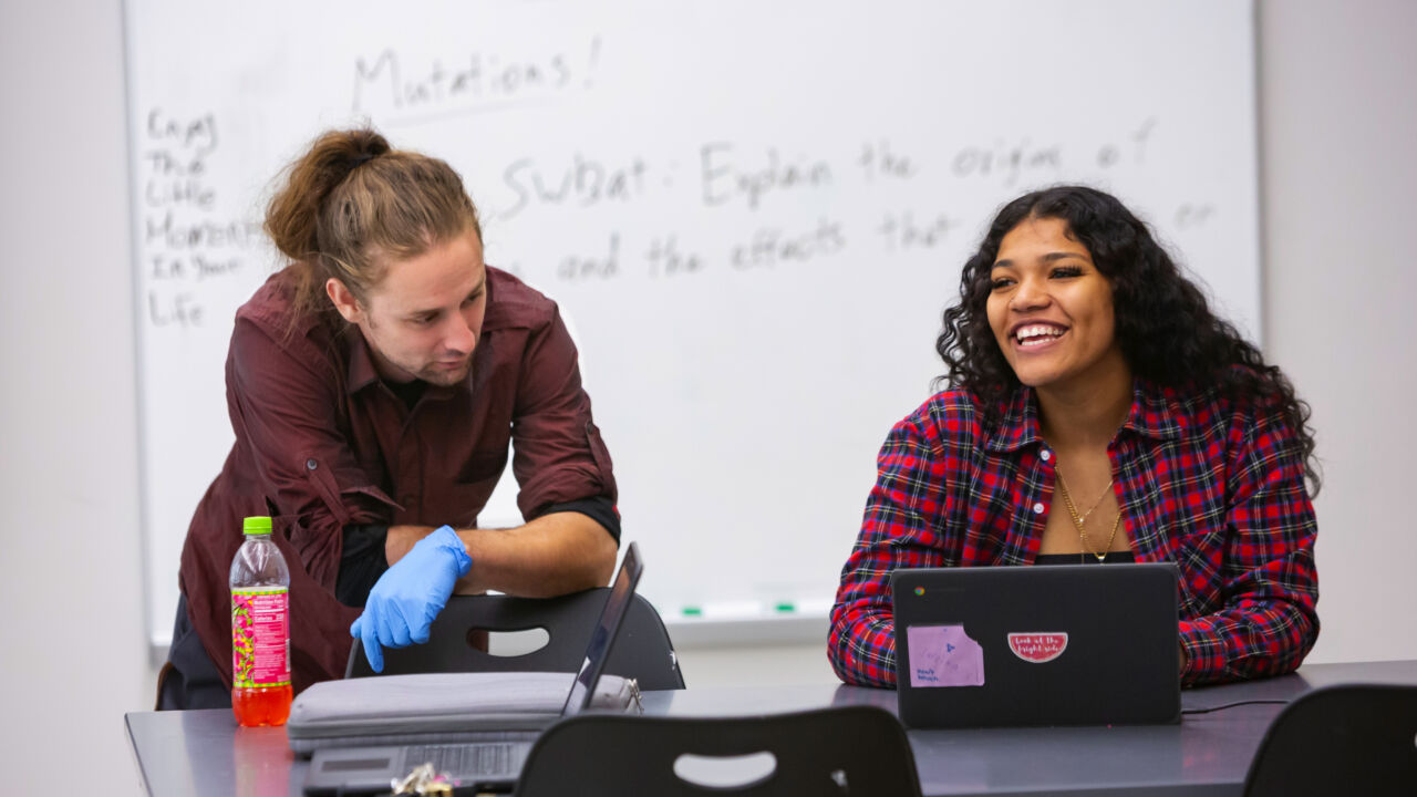 Student sitting at a desk and looking across the room smiling