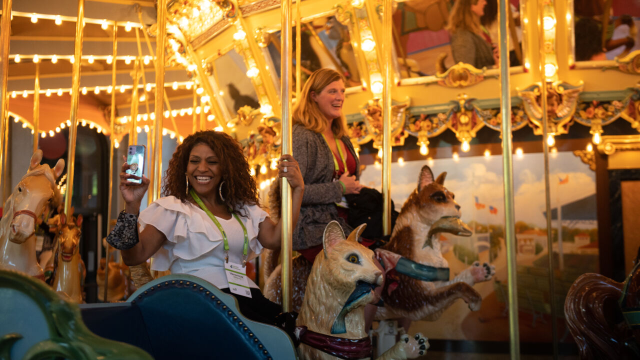 Two smiling women on a golden lit up carousel