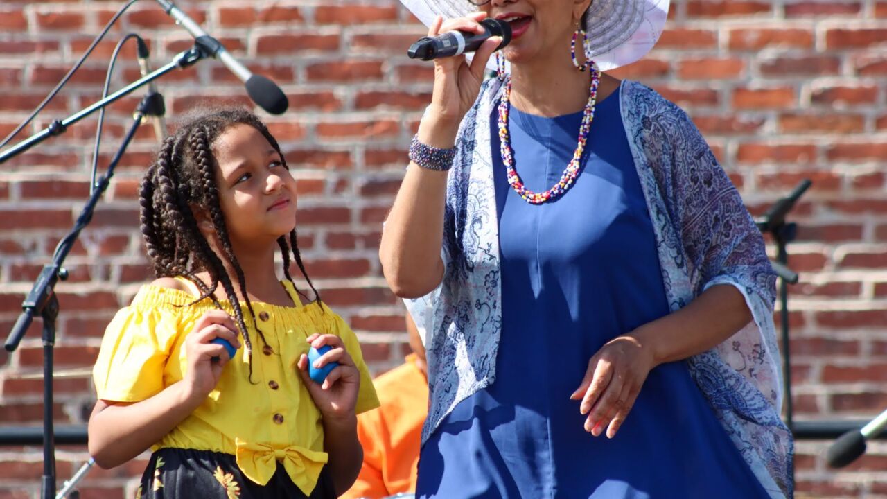 Woman and young girl on an outdoor stage singing