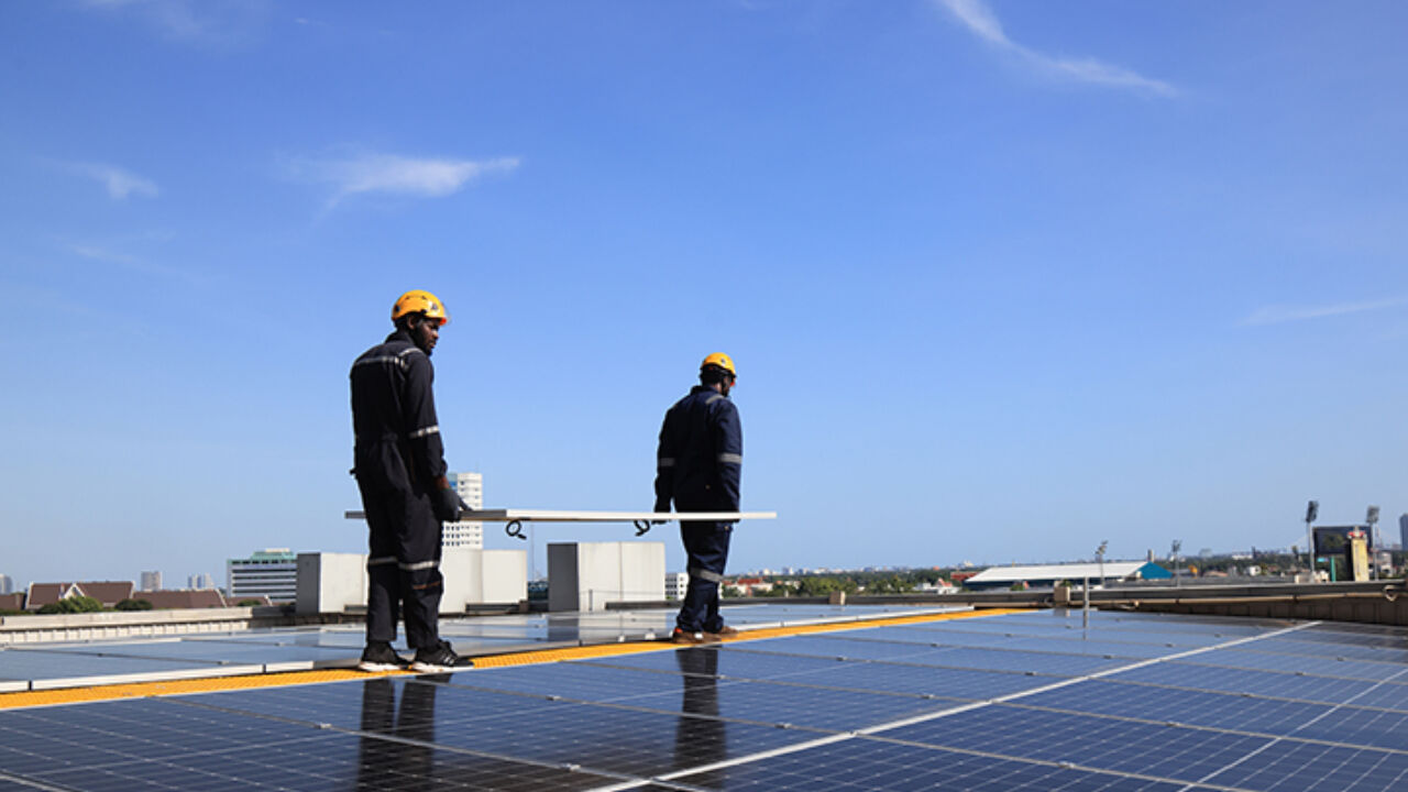 Two men carrying a solar panel during a roof installation