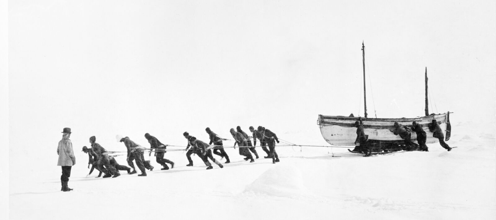 Men work together to haul a boat ashore.