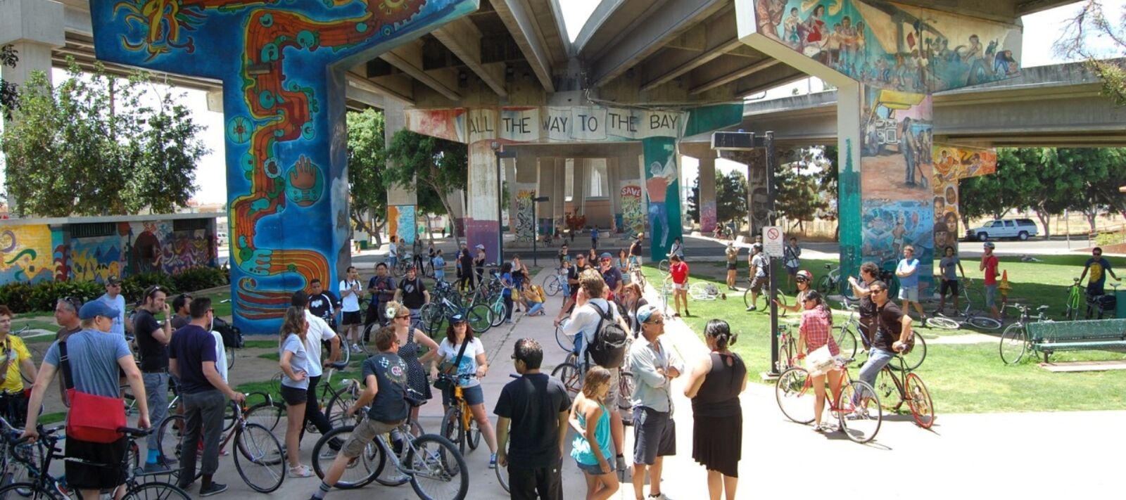 Bikers and pedestrians hang out under a street mural.