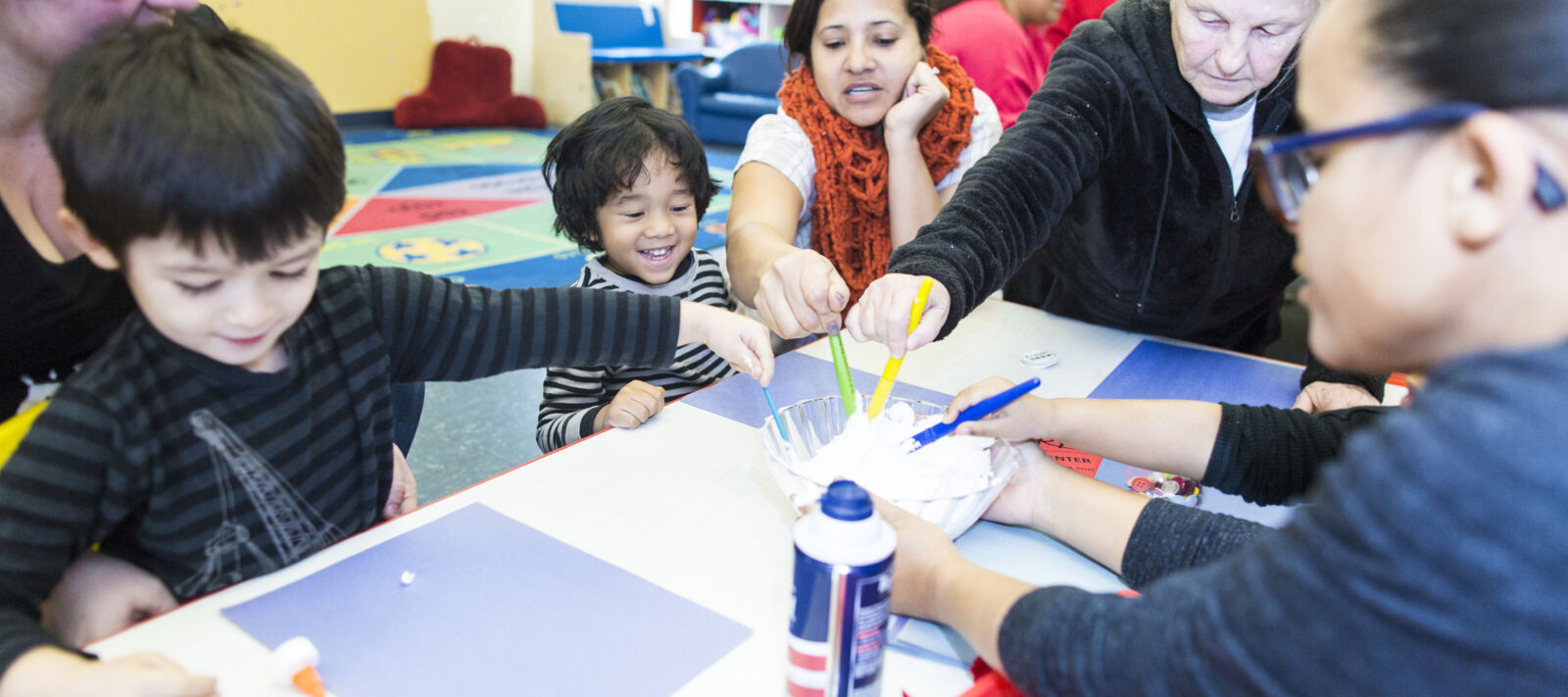 Kids and their parents paint a snowman.
