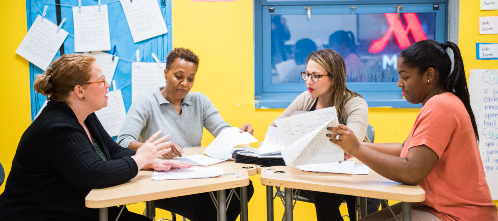 Four teachers work around a table looking at papers.