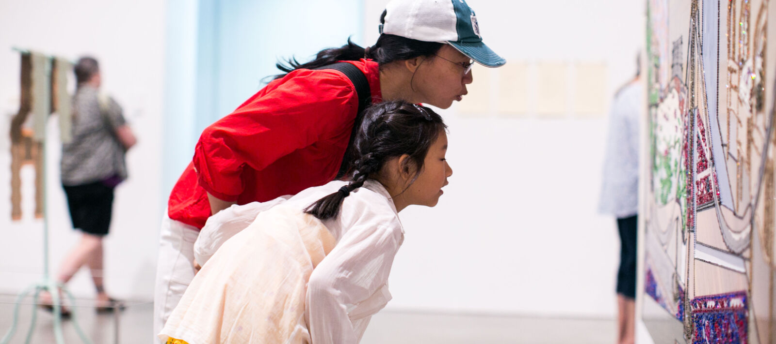 Mom and daughter look at art on the wall together.