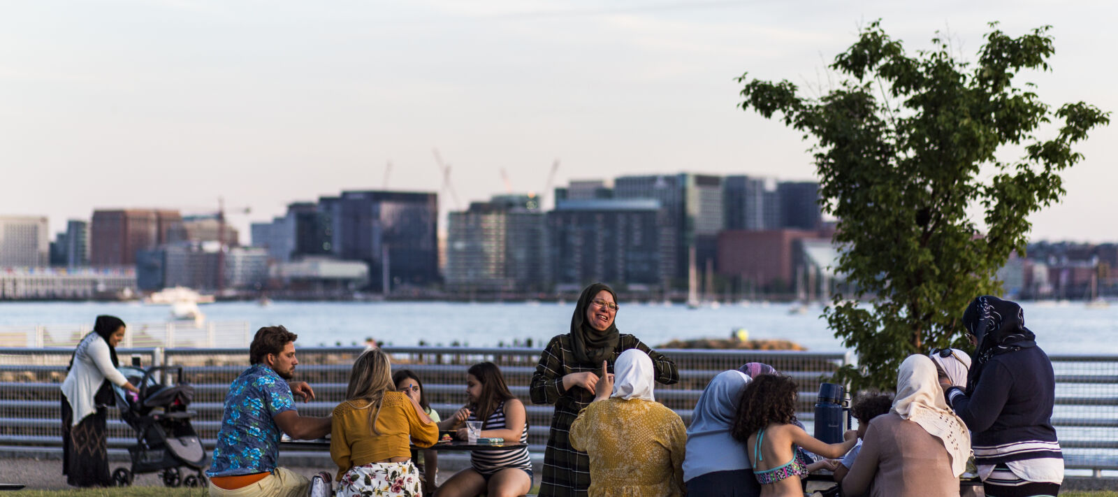 People laugh at picnic tables on Boston's waterfront.