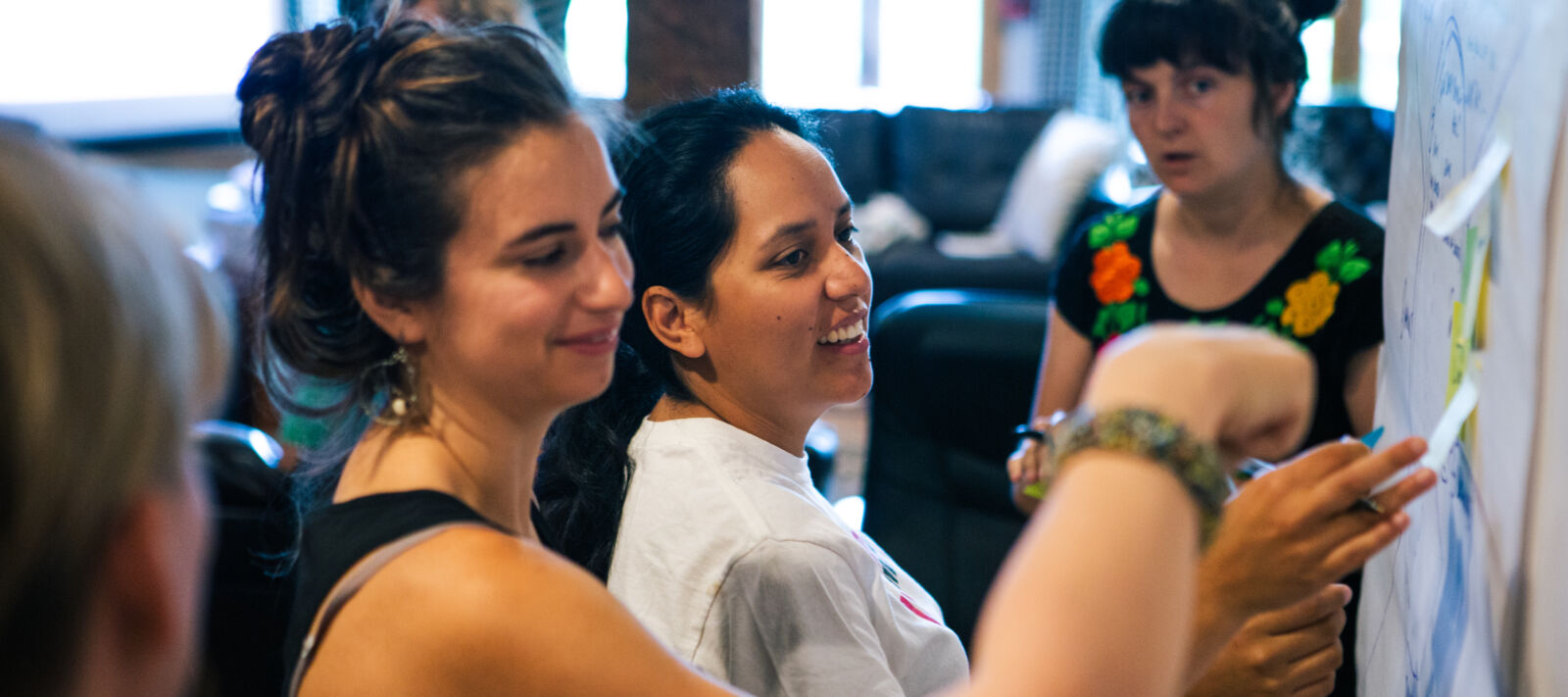 Adults stick post its to a wall.