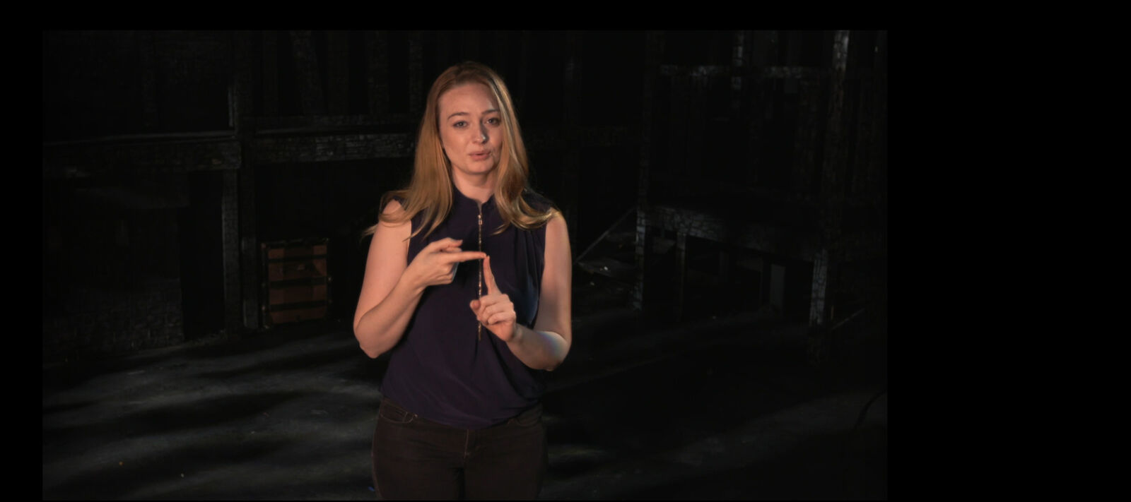 A woman uses American sign language on stage.