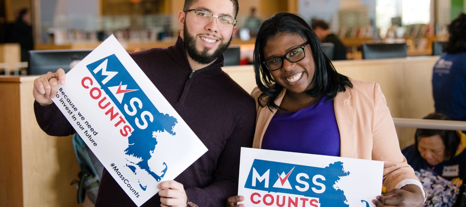 Two people hold up signs in support of the Census.