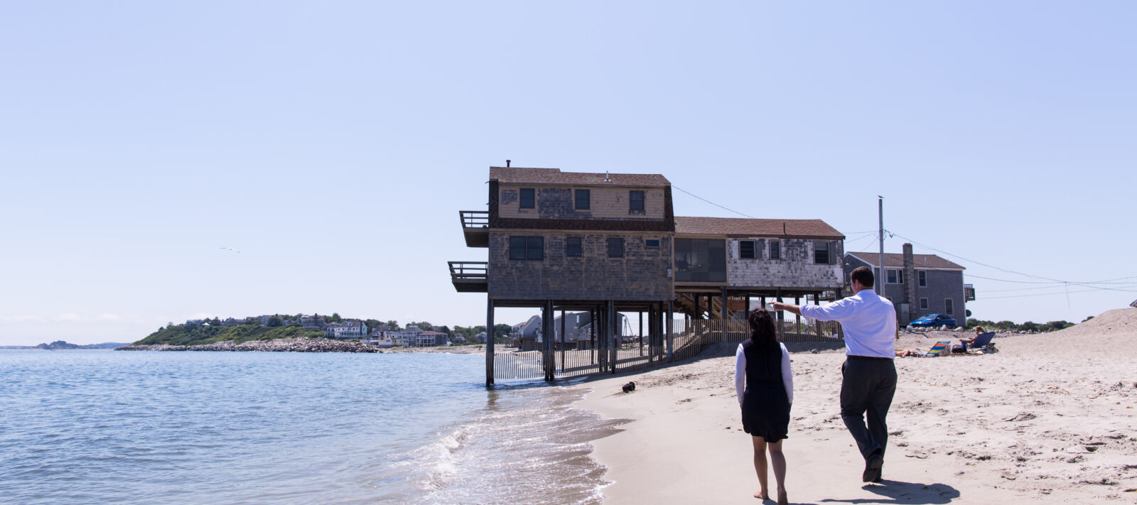 Two people walk along the beach.