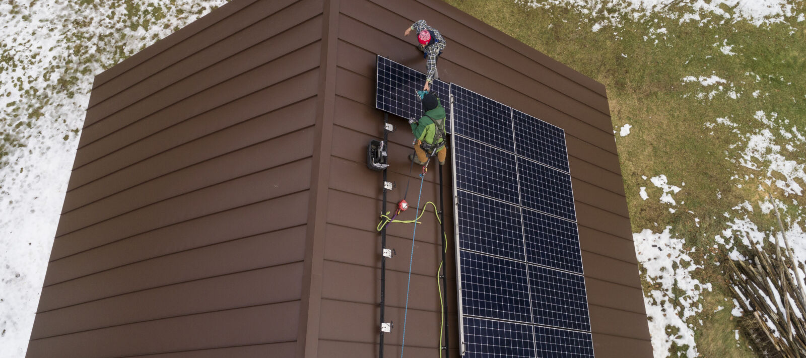 Two men install solar panels on the roof of a home.