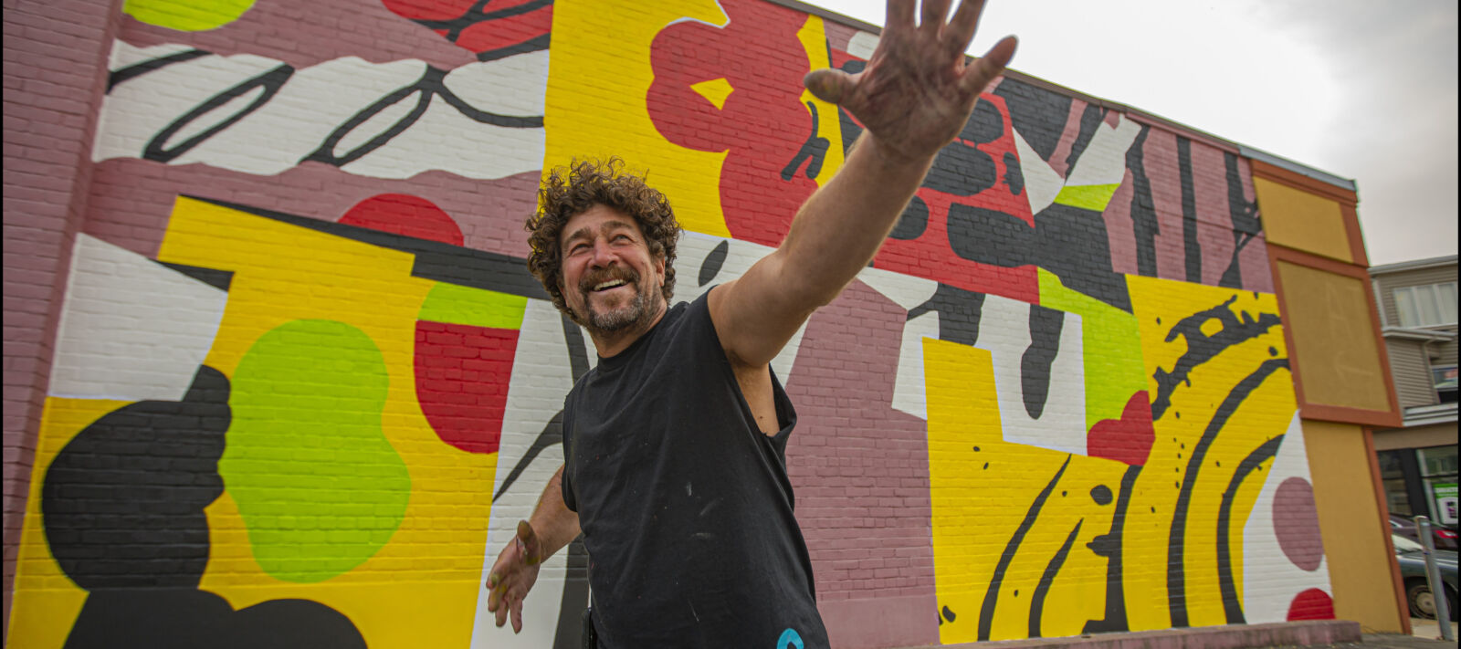A man poses happily with a mural.
