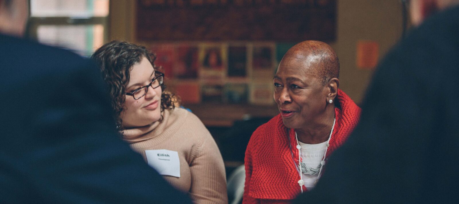Two women talk at a round table.