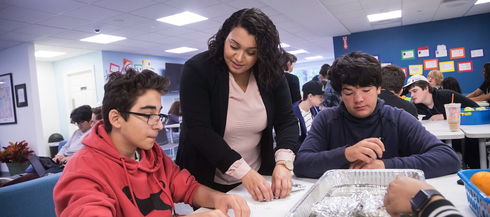 A teacher works with students on an experiment.