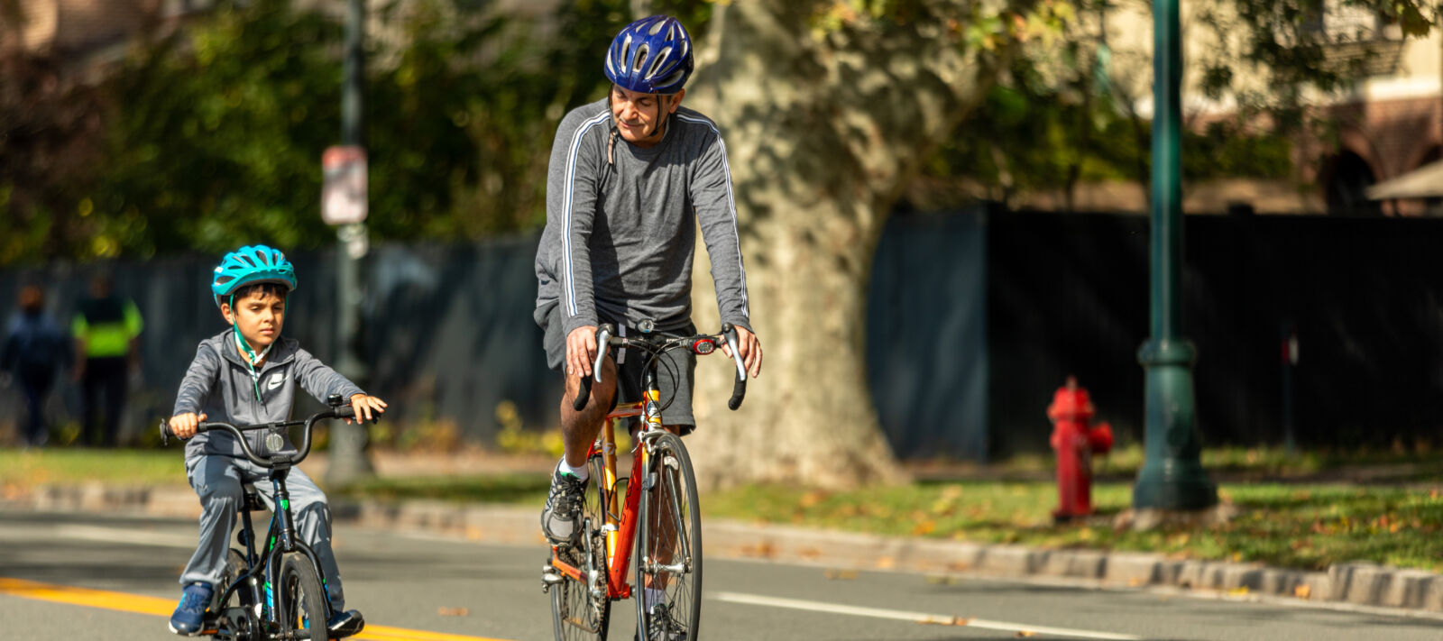 A grandfather and grandson bike outside.