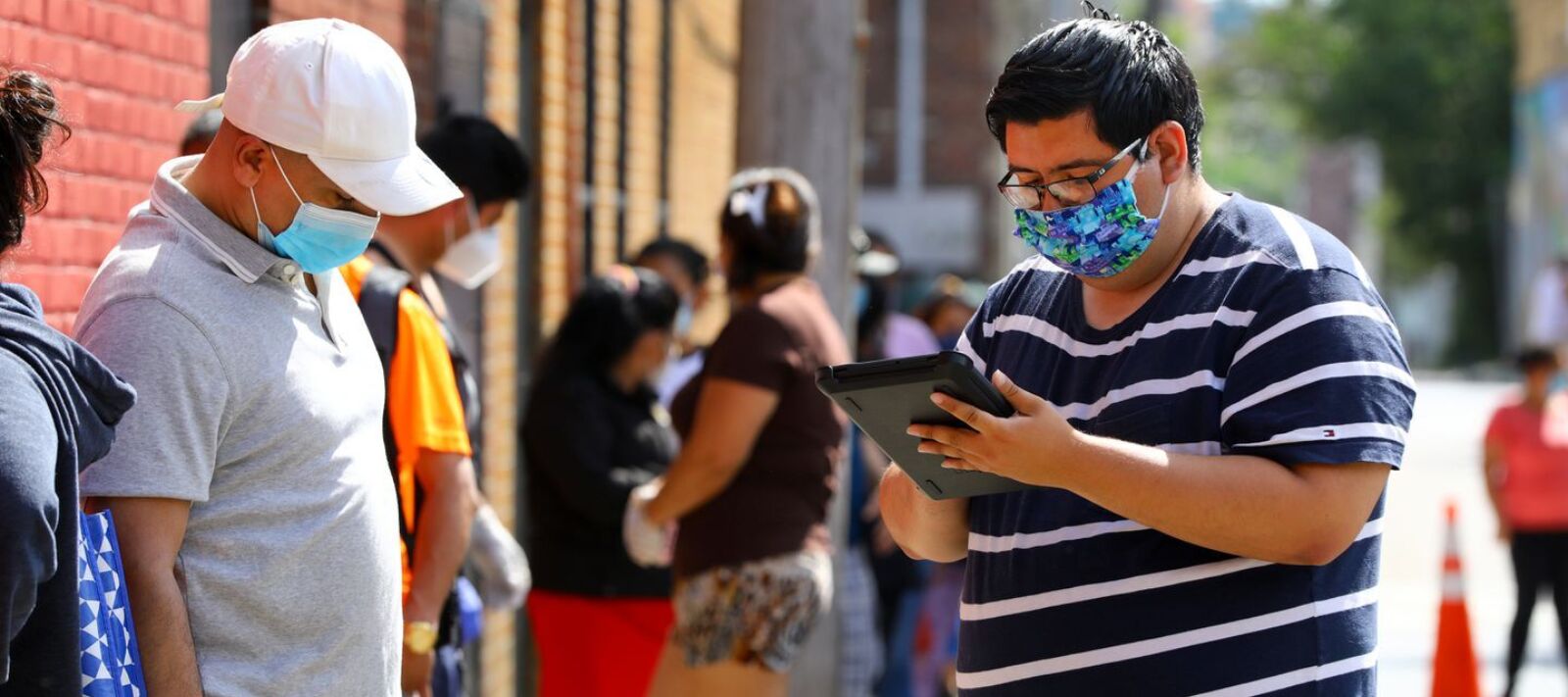 Census 2020 field organizer interviews a resident in the food pantry line at the Chelsea Collaborative during the coronavirus pandemic.