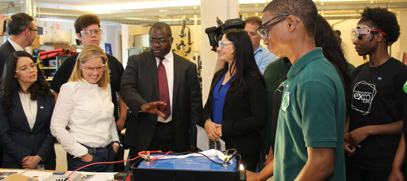 A student shows off technology to a group of visiting adults.