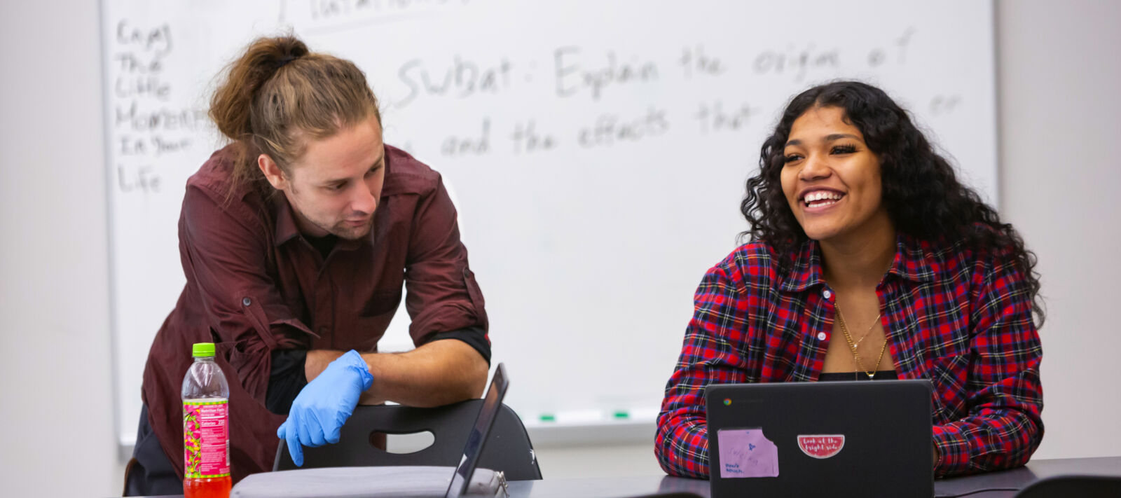 Student sitting at a desk and looking across the room smiling