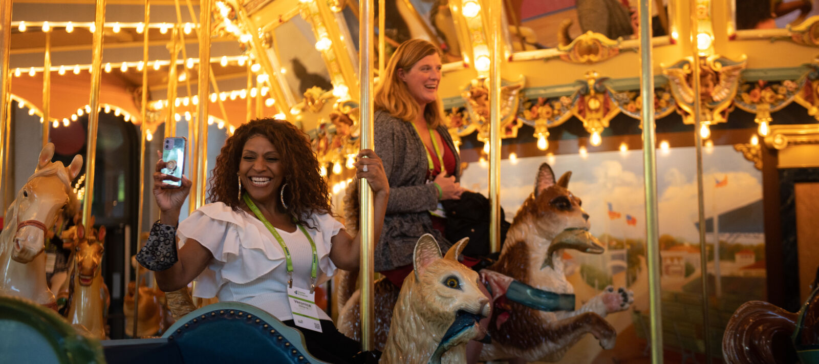 Two smiling women on a golden lit up carousel