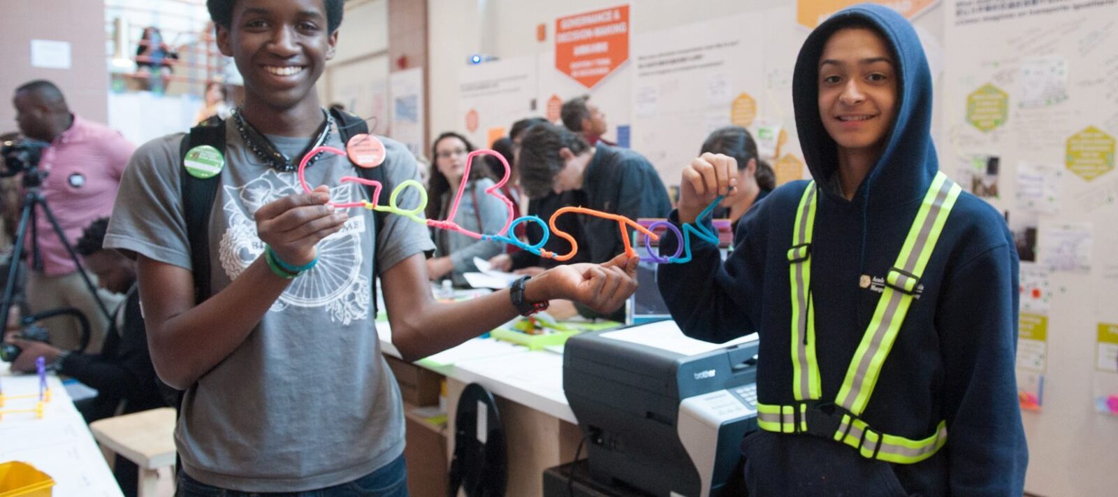 Two teenagers hold up a straw sign that reads "Go Boston 2030".