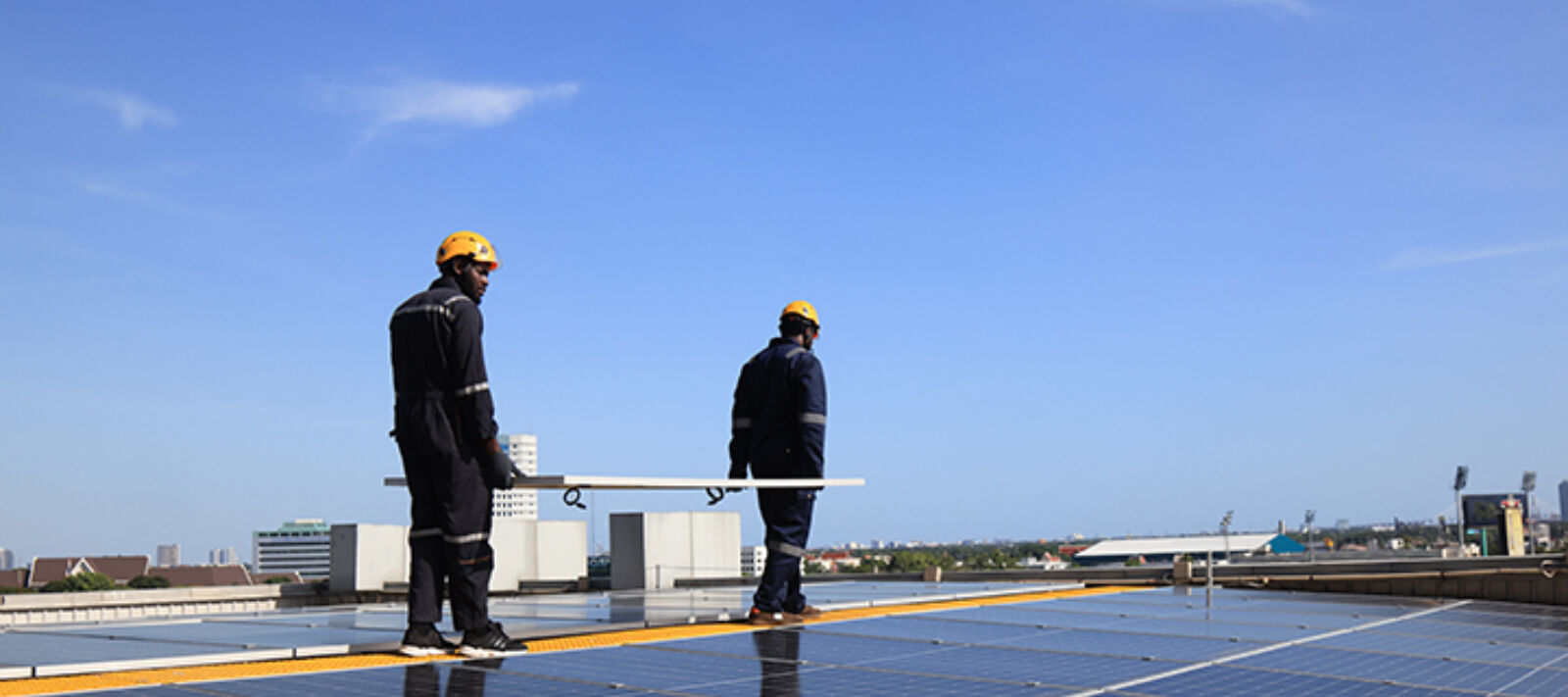 Two men carrying a solar panel during a roof installation