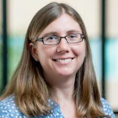 middle-aged woman with dirty blonde hair wearing glasses and smiling