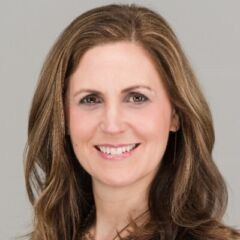 Headshot of white woman with light brown hair smiling and looking into the camera.
