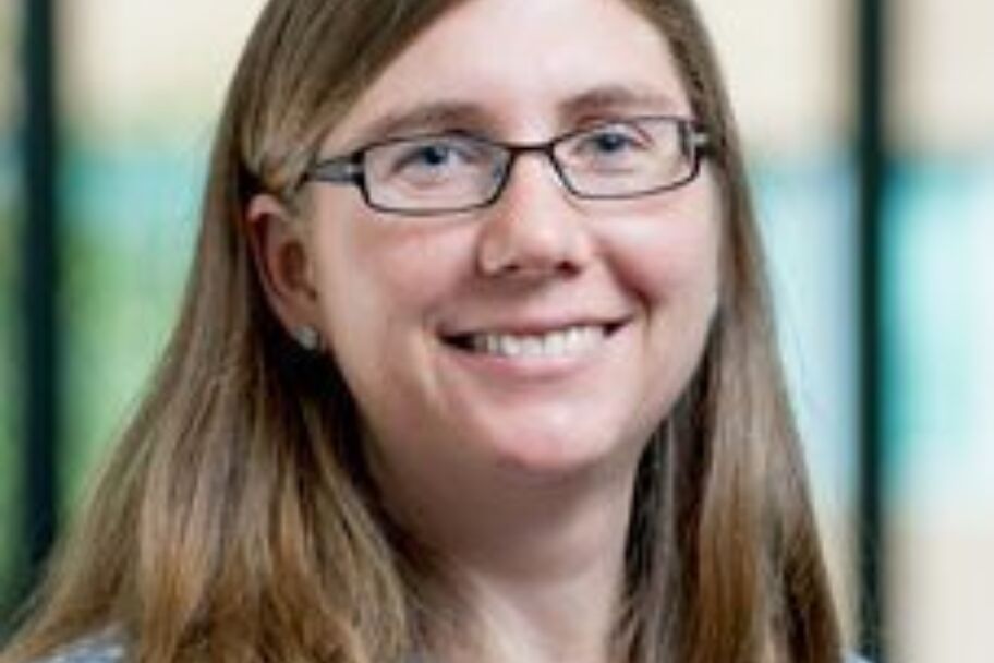 middle-aged woman with dirty blonde hair wearing glasses and smiling