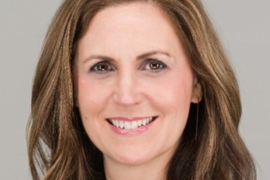 Headshot of white woman with light brown hair smiling and looking into the camera.