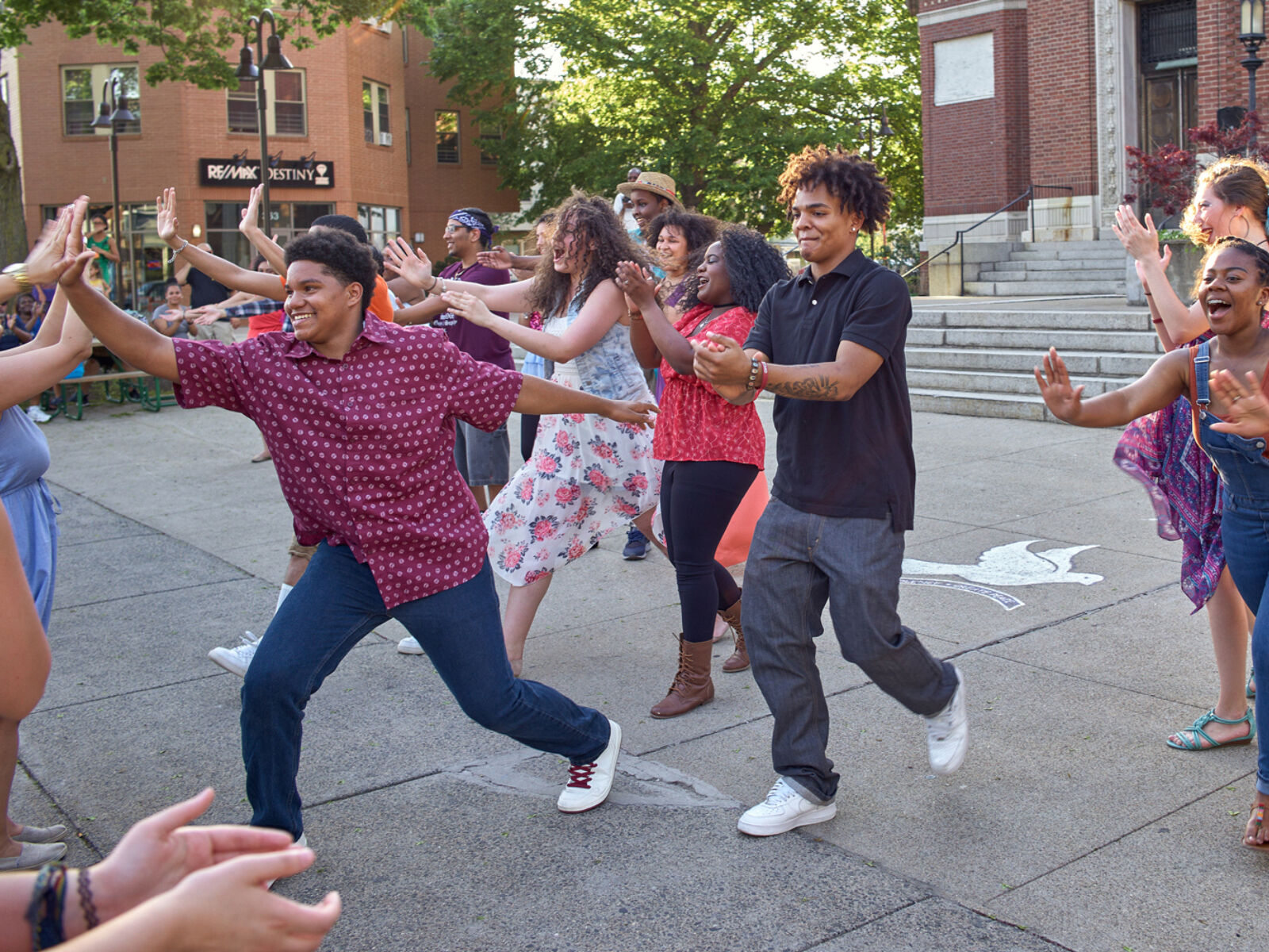 A group of happy, young people clap and high five during an outdoor dance performance