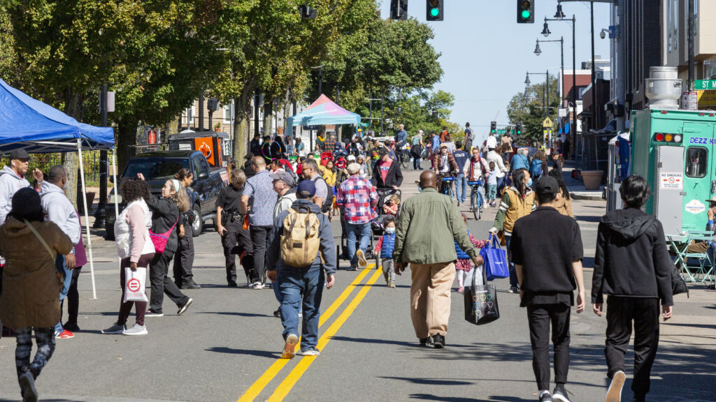 People fill the street to walk, mingle, and spend time during a Dot Ave Open Streets event