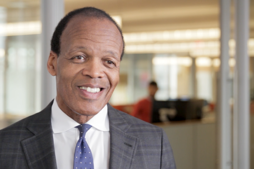 Lee Pelton, one of Barr's trustees, appears in Barr's offices. He smiles, wearing a neat suit and tie.